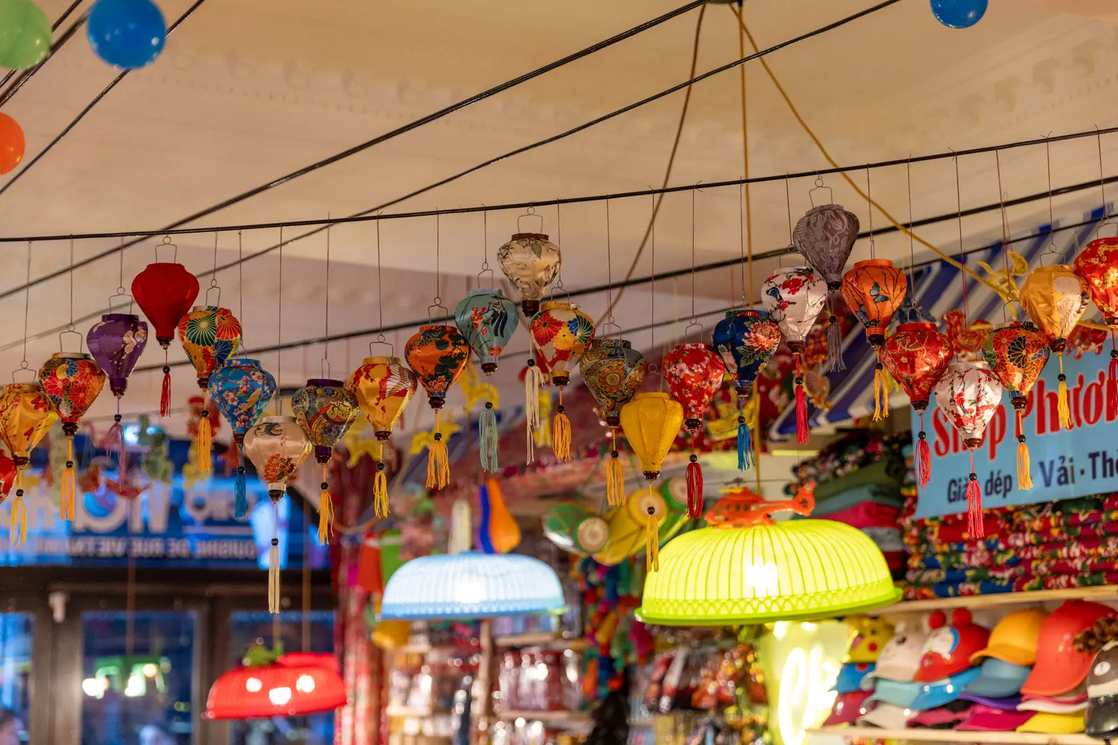 Lanternes en soie multicolores suspendues au-dessus d'un étal de marché vietnamien.